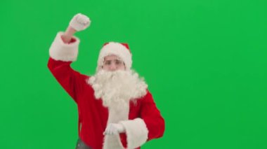Noel ve Yeni Yıl yaratıcı konsepti. Krom anahtar yeşil ekranda Noel Baba kılığında bir adam portresi. Kırmızı elbiseli Noel Baba komik dans ediyor..