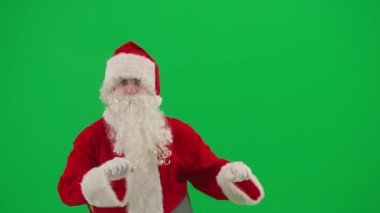 Noel ve Yeni Yıl yaratıcı konsepti. Krom anahtar yeşil ekranda Noel Baba kılığında bir adam portresi. Kırmızı elbiseli Noel Baba komik dans ediyor..