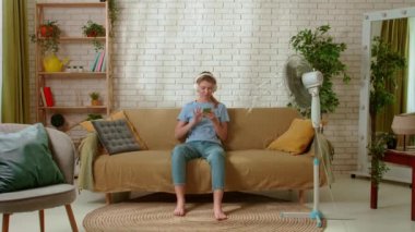 Genç bir bayan evde vakit geçiriyor. Genç milenyum kadını oturma odasındaki kanepede oturmuş kulaklıklarla akıllı telefondan müzik dinliyor ve dans ediyor. Sıkıcılık günlük yaşam konsepti.