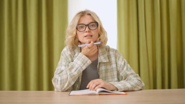 Çevrimiçi kursa katılan genç kişi. Evde çalışan, masa başında oturan bilgisayar dersini dinleyen, not defterine yazan bir üniversite öğrencisi. Modern online eğitim.