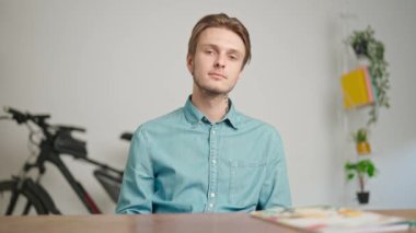 Çevrimiçi kursa katılan genç kişi. Erkek üniversite öğrencisi evde çalışıyor, masada oturuyor, internette ders dinliyor, gülümsüyor. Modern online eğitim.