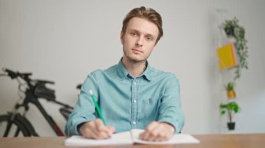 Çevrimiçi kursa katılan genç kişi. Erkek üniversite öğrencisi evde çalışıyor, masada oturuyor öğretmenle konuşuyor ve soruları cevaplıyor, internette dinleme dersi veriyor. Modern online eğitim