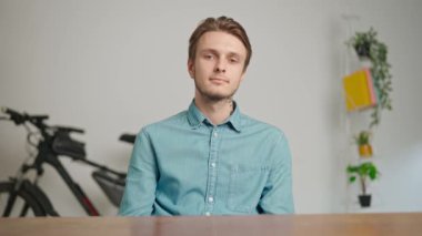 Çevrimiçi kursa katılan genç kişi. Erkek üniversite öğrencisi evde okuyor, masada oturuyor, öğretmenini selamlıyor ve bilgisayar dersini izliyor. Modern online eğitim.