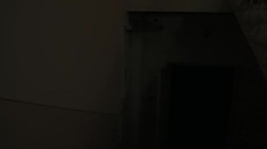 Genç bir kadın karanlıkta merdivenlerde. Beyaz elbiseli, korkunç maskeli, elleri kanlı, karanlık perili bir evde merdivenlerde oturan ürkütücü hayalet kadın kameraya bakar. Cadılar Bayramı korku konsepti.