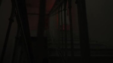 Genç bir kadın karanlıkta merdivenlerde. Beyaz elbiseli ve korkunç makyajlı ürkütücü hayalet kadın karanlık perili evde merdivenlerde tek başına dikiliyor. Cadılar Bayramı korku reklam konsepti.