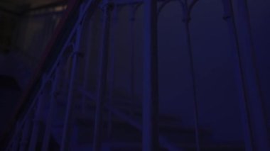 Genç bir kadın karanlıkta merdivenlerde. Beyaz elbiseli ve korkunç makyajlı ürkütücü hayalet kadın karanlık perili evde merdivenlerde tek başına oturuyor. Cadılar Bayramı korku reklam konsepti.