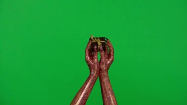 Stüdyoda jestler gösteren korkunç bir el. Korkunç cadılar bayramı canavarı. Elinde küçük hediye kutusu olan parıltılı sümüklü el. Krom anahtar yeşil ekran arka planında izole edilmiş..