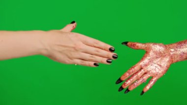 Stüdyoda jestler gösteren korkunç bir el. Korkunç cadılar bayramı canavarı. Parlak balçık içinde el ve kadın eliyle tokalaşıyor. Krom anahtar yeşil ekran arka planında izole edilmiş..