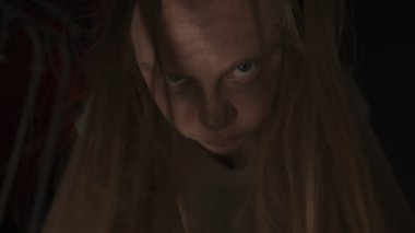 Genç bir kadın karanlıkta merdivenlerde. Beyaz elbiseli ve korkunç makyajlı ürkütücü hayalet kadın karanlık perili evde tek başına kameraya el feneriyle bakıyor, kapat. Cadılar Bayramı korku konsepti.