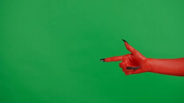 Stüdyoda jestler gösteren korkunç bir el. Korkunç cadılar bayramı canavarı kırmızı boyalı, siyah tırnaklı, parmağını yana doğru gösteren, krom anahtar yeşil ekran arka planda izole edilmiş, çalışma alanı modeli..