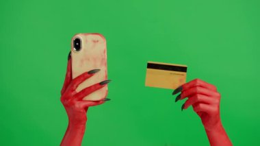Stüdyoda jestler gösteren korkunç bir el. Korkunç cadılar bayramı canavarı kırmızı boyalı siyah tırnaklı el akıllı telefon uygulamasında kart numarası, krom anahtar yeşil ekranda izole edilmiş, çalışma alanı modeli.