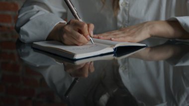 Kağıt üzerinde kadın metni. Ofis masasında oturan bir iş kadını süt ürünleri bölümünde kalemle notlar açıp yazıyor. Konsantre bir kişi fikirler ve görevler yazıyor. Yakın çekim..