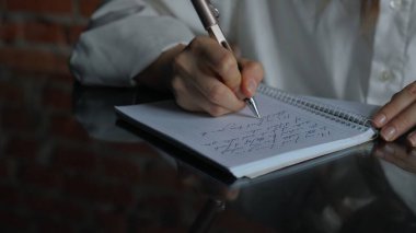 Kağıt üzerinde kadın metni. Ofis masasında oturan bir iş kadını süt ürünleri bölümünde kalemle notlar açıp yazıyor. Konsantre bir kişi fikirler ve görevler yazıyor. Yakın çekim..