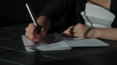 Kağıt üzerinde kadın metni. İş kadını büro masasında oturmuş kalemle notlar alıyor. Konsantre olmuş, düşüncelerini ve planlarını yazıyor. Yakın çekim yapıyor..