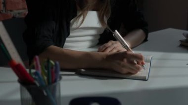 Kağıt üzerinde kadın metni. Ofis masasında oturan iş kadını. Süt ürünleri defterine kalemle hatıra notları yazıyor. Düşüncelerini ve fikirlerini yazan kişi..