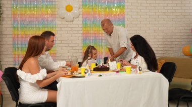 Mutlu çok nesilli bir aile evde doğum gününü kutlar. Büyükbaba ve torun herkes doğum günü pastası yerken telefona bakıyorlar. Tatil ve kutlama kavramı.