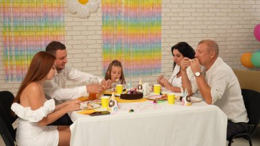Mutlu çok nesilli bir aile doğum gününü kendi evinde kutlar. Masadaki herkes şenlikli bir akşam yemeği yerken neşeli bir sohbete daldı. Parti ve kutlama konsepti..