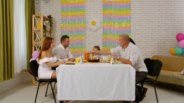 Mutlu çok nesilli bir aile doğum gününü kendi evinde kutlar. Herkes mutlu bir şekilde sohbet ederken büyükbaba doğum günü kızı için meyve suyu koyuyor. Tatil ve kutlama konsepti.