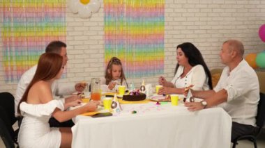 Mutlu çok nesilli bir aile doğum gününü kendi evinde kutlar. Masadaki herkes şenlikli bir akşam yemeği yerken neşeli bir sohbete daldı. Parti ve kutlama konsepti..