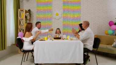 Mutlu çok nesilli bir aile doğum gününü kendi evinde kutlar. Herkes bir şenlik masasında oturup sevinçle kadeh kaldırır ve tebrik eder. Tatil ve kutlama konsepti.