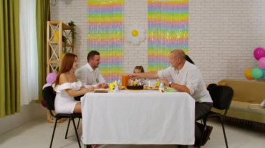 Mutlu çok nesilli bir aile doğum gününü kendi evinde kutlar. Herkes mutlu bir şekilde sohbet ederken büyükbaba doğum günü kızı için meyve suyu koyuyor. Tatil ve kutlama konsepti.