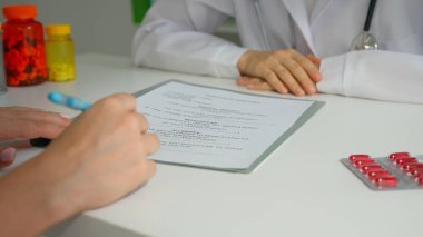 Ofiste çalışan bir tıp uzmanı. Masasında oturan beyaz önlüklü kadın verileri hasta ile kontrol ediyor, dosyada tıbbi form belgeleri yazıyor ve şarkı söylüyor. Tıbbi tedavi kavramı.