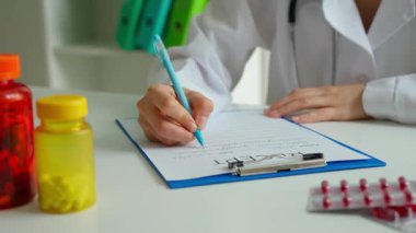Ofiste çalışan bir tıp uzmanı. Masasında steteskoplu beyaz önlüklü kadın doktor reçete yazıyor, evrak dolduruyor. Tıbbi tedavi kavramı.