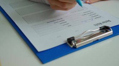 Ofiste çalışan bir tıp uzmanı. Beyaz önlüklü kadın doktor masa başında oturmuş randevu yazıyor, hasta hakkındaki tıbbi belgeleri dolduruyor, kapatıyor. Tıbbi tedavi kavramı.