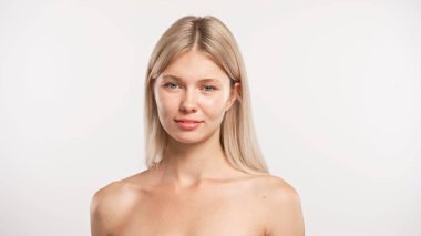 Çekici kadın model güzellik tedavisi yapıyor. Genç sarışın kadın kameraya bakıyor ve gülümsüyor doğal olarak, pozitif ifade, beyaz stüdyo arka planında izole edilmiş. Güzel cilt bakımı konsepti