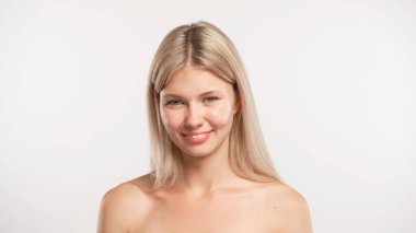 Çekici kadın model güzellik tedavisi yapıyor. Genç sarışın kadın kameraya bakıyor ve gülümsüyor doğal olarak, pozitif ifade, beyaz stüdyo arka planında izole edilmiş. Güzel cilt bakımı konsepti