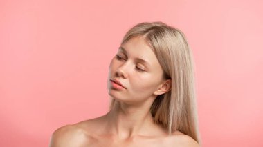 Çekici kadın model güzellik tedavisi yapıyor. Kameraya poz veren genç sarışın kadın, olumlu ifade, pembe stüdyo arka planında izole edilmiş. Güzel cilt bakımı konsepti