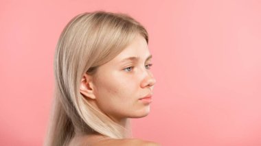 Çekici kadın model güzellik tedavisi yapıyor. Kameraya poz veren genç sarışın kadın, olumlu ifade, pembe stüdyo arka planında izole edilmiş. Güzel cilt bakımı konsepti