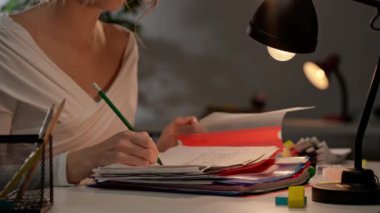 Kadın çalışanlar raporlarla çalışır. İşkolik bir kadın ofis masasında oturmuş renkli dosya klasörlerinin içinde kalem ile kağıt kağıtları imzalıyor. Bürokrasi iş konsepti.