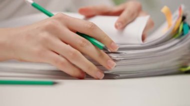 Kadın çalışanlar raporlarla çalışır. Ofis masasında oturan kadın renkli ataçlı kağıt yığınını düzenliyor ve imzalıyor. Kapat. Bürokrasi iş konsepti.