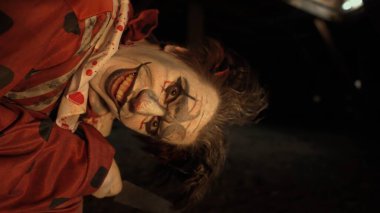 Karanlıkta çatıda korkunç deli bir palyaço. Mahvolmuş evde makyajlı palyaço kılığındaki manyak katil kameraya bakıyor, konuşuyor, gülümsüyor ve çıldırıyor. Cadılar Bayramı gerilim konsepti.