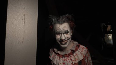 Karanlıkta çatıda korkunç deli bir palyaço. Mahvolmuş evde makyajlı palyaço kılığındaki manyak katil kameraya bakıyor, konuşuyor, gülümsüyor ve çıldırıyor. Cadılar Bayramı gerilim konsepti.