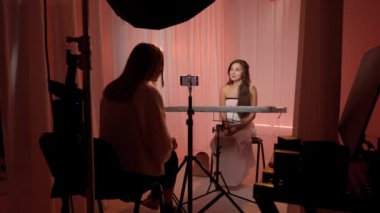 Stüdyoda poz veren güzel bir kadın model. Makyajlı ve saç stili olan kadın kameraya gülümsüyor pürüzsüz tenine dokunuyor, uçan pembe kumaş stüdyosu arka planında. Güzellik ve sağlık konsepti.