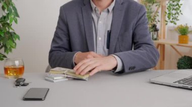 Hizmet ya da ürün için farklı ödeme türleri kullanan bir adam. Ofis masasında oturan bir iş adamı elinde tomar tomar parayla banknotları sayıyor. Özel ticari ve iş ödemeleri.