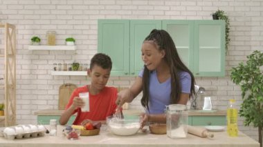 Afro-Amerikalı mutlu aile mutfakta yemek hazırlıyor. Oğlum hamur karışımına süt ekle ve anne karışımı karıştırsın. Birlikte vakit geçirip, sağlıklı bir hayat sürüyoruz..