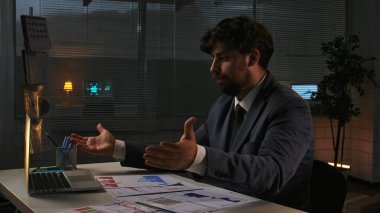 Odaklanmış profesyonel erkek, geç saatlere kadar çalışıyor. Yetişkin bir iş adamı yönetici, geceleri ofiste dizüstü bilgisayarla çalışır, el ele tutuşur, üzgün bir ifade, hayal kırıklığına uğramış bir jest..