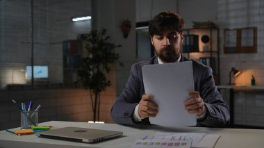 Odaklanmış profesyonel erkek, geç saatlere kadar çalışıyor. Yetişkin iş adamı yöneticisi, masa başında oturuyor, geceleri fazla mesai yapıyor, bilgisayarını kapatıyor, evrakları düzenliyor..