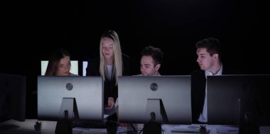 Yönetim kurulu başkanı ve ekibi ofiste çalışıyor. Kadın ve erkek liderler karanlık ofiste monitörlerle, yıl sonu kurumsal toplantısıyla masa başında çalışıyor. Patron gazete okuyan takım üyelerine bakıyor..