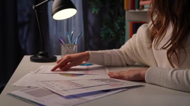 Ofis çalışanı fazla mesai yapıyor. Genç iş kadını gece geç saatlere kadar ofiste çalışıyor, mali bilgili kağıt dökümanlarına bakıyor, verileri kontrol ediyor..