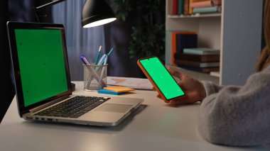 Ofis çalışanı fazla mesai yapıyor. Yetişkin iş kadını ofiste geç saatlere kadar çalışıyor. Laptop ve krom anahtar yeşil ekranlı akıllı telefon, çalışma alanı modeli..