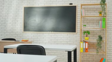 Ekipman ve mobilyalarla dolu üniversite sınıfı. Masaları, sandalyeleri ve karatahtası olan boş parlak okul sınıfı, pencereden güneş ışınları, öğrenmek ve öğretmek için çalışma alanı.