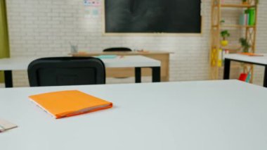 Ekipman ve mobilyalarla dolu üniversite sınıfı. Gün ışığında masaları, sandalyeleri ve karatahtası olan boş parlak okul sınıfı, öğrenmek ve öğretmek için çalışma alanı. Masaların üzerinde duran defterler ve kalemler.