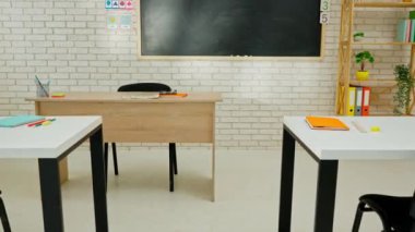 Ekipman ve mobilyalarla dolu üniversite sınıfı. Masaları, sandalyeleri ve tahtası olan boş bir ilkokul sınıfı. Öğrenme ve öğretme için çalışma alanı. Duvarda matematik kartları, masalarda not defterleri.