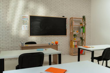 Ekipman ve mobilyalarla dolu üniversite sınıfı. Gün ışığında masaları, sandalyeleri ve karatahtası olan boş okul astronomi sınıfı, öğrenmek ve öğretmek için çalışma alanı. Gezegen modelli masalar, yan çekim.