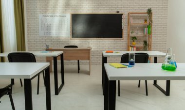 Ekipman ve mobilyalarla dolu üniversite odası. Masaları, sandalyeleri ve tahtası olan boş bir kimya sınıfı. Eğitim ve öğretim için çalışma alanı. Masanın arkasında cam şişeler ve sıvılar var..