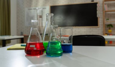 Ekipman ve mobilyalarla dolu üniversite odası. Masaları, sandalyeleri ve tahtası olan boş bir kimya sınıfı. Eğitim ve öğretim için çalışma alanı. Masanın üzerinde renkli sıvılar olan cam şişeler..